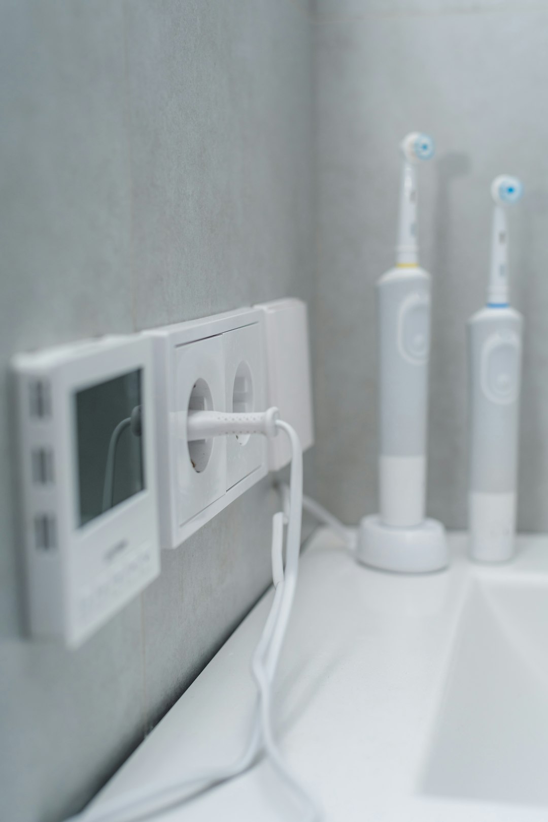 a-bathroom-with-three-electric-toothbrushes-on-the-wall-cn8c3opyvki